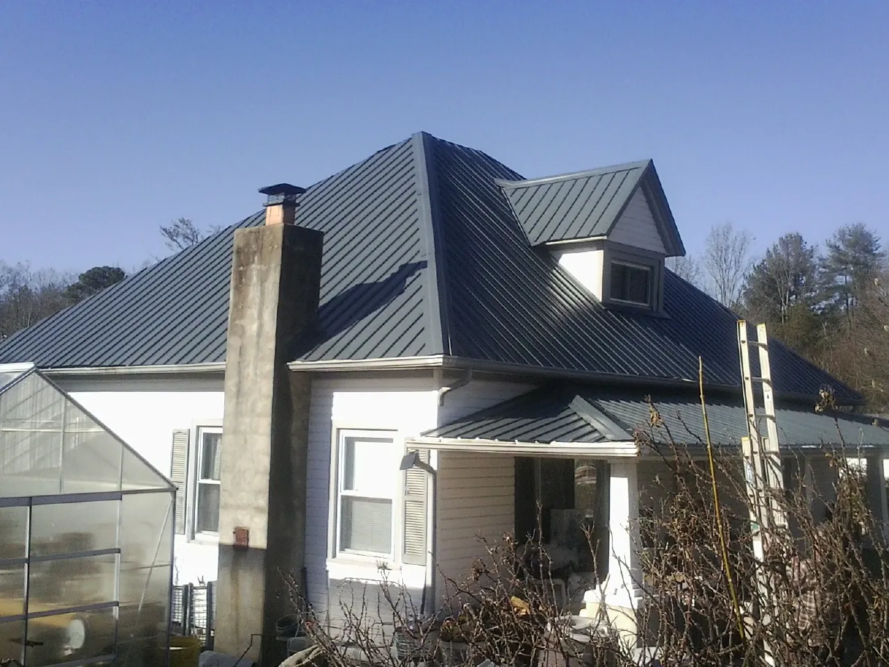 Dark blue standing seam metal roof on a white farmhouse with dormer — Slate & Tile Roof Repair by Roofing Brothers in West Salisbury