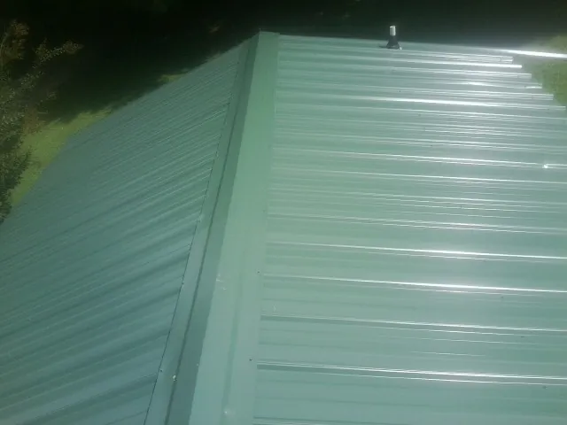 New green metal panels meeting at the ridge of a roof — Flat Roof Repair work by our crew in West Salisbury