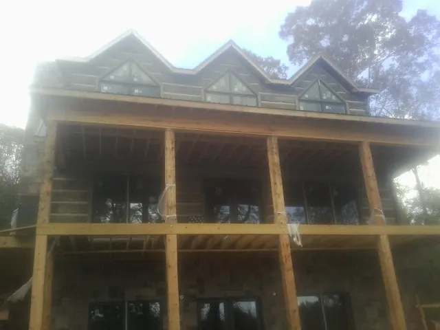 Dormers and porch framing on a large log home under construction — Roof Coating work by our crew in West Salisbury