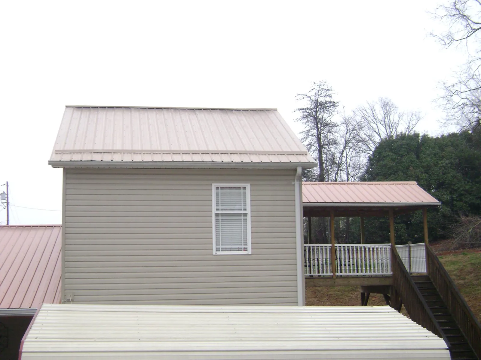 Tan metal roofs on a two story addition and attached porch, from a Roof Replacement job in West Salisbury