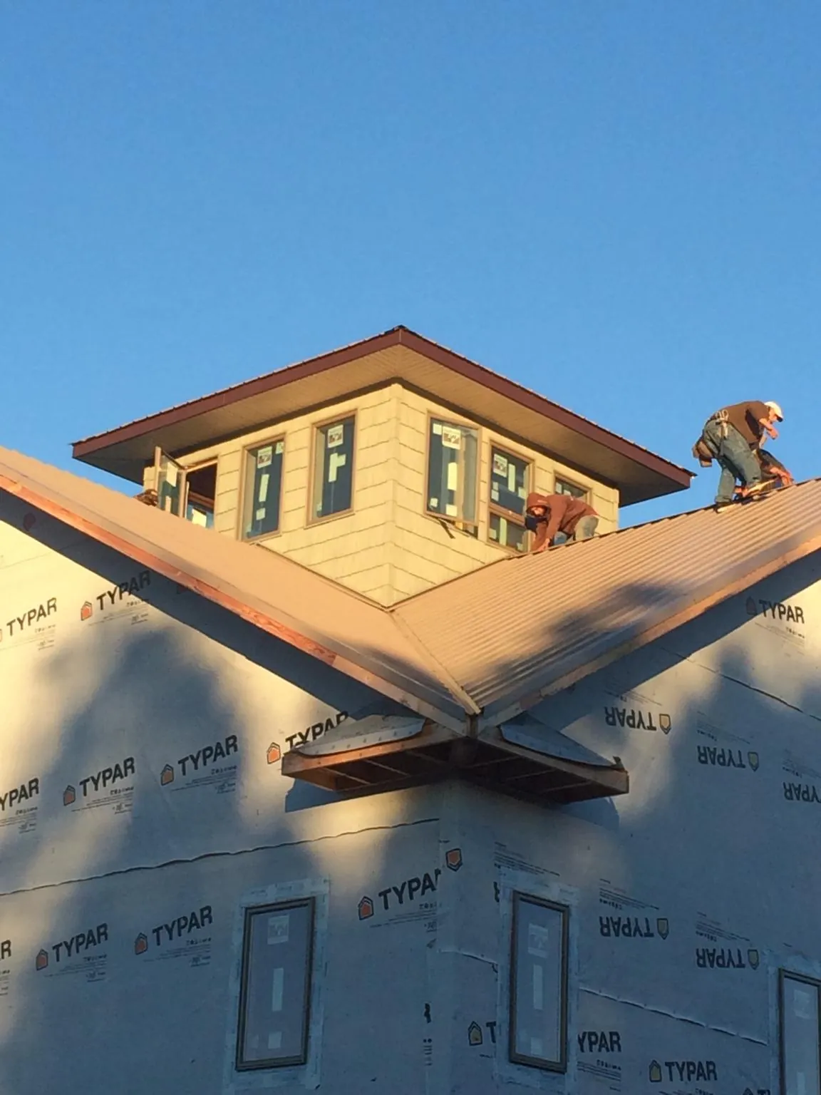 Roofers working around a rooftop cupola on a new metal roof at sunset — Roof Waterproofing in West Salisbury by Roofing Brothers